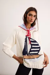 Sweater de punto color marfil con diseño de velero en la parte frontal, cuello con capucha y cordón rojo de ajuste.