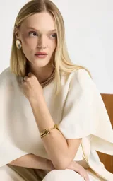 Pulsera rígida de metal dorado con diseño circular abierto y acabado pulido. Presenta una estructura lisa con extremos redondeados y ligeramente cónicos.