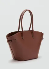 Bolso tipo tote marrón de poliuretano, de gran tamaño, con dos asas y cierre de botón magnético. Detalle de costuras visibles y laterales ajustables.