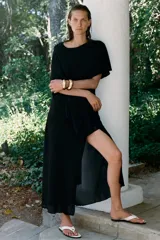 Vestido largo negro de la colección ZW de Zara, confeccionado en tejido satinado. Cuenta con un diseño asimétrico que incorpora una capa superpuesta y un corte fluido.