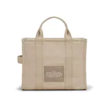 Bolso tote de lona color negro con estampado frontal en blanco que reza 'THE TOTE BAG MARC JACOBS'. Cuenta con doble asa superior, cierre de cremallera y correa larga ajustable y extraíble.