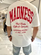 Remera oversize blanca de manga corta, con estampa en la espalda en color rojo con la inscripción 'Madness' y tipografía estilo universitario.