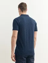 Remera polo azul marino con estampado de pequeños puntos blancos, cuello clásico con tres botones y mangas cortas.