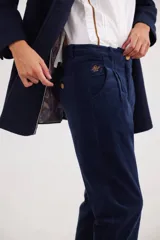 Pantalón recto de tiro medio confeccionado en pana con lycra. Presenta pinzas frontales, bolsillos laterales y traseros, y cierre con botón dorado. El diseño destaca por el detalle de paño espigado en el interior del ruedo, visible al doblarlo, y un pin bordado decorativo en el bolsillo delantero.