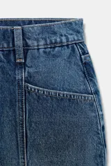 Falda pantalón de tiro medio confeccionada en tejido denim azul con costuras verticales decorativas, bolsillos delanteros y cierre frontal con cremallera y botón metálico.