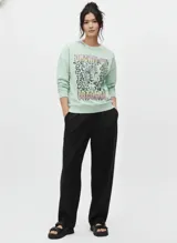 Buzo de algodón y poliéster color verde menta, con cuello redondo y manga larga. Presenta un estampado frontal con un leopardo y texto en tonos neón.
