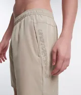 Bermuda deportiva color verde oliva, con cintura elástica, cordón interior, bolsillos laterales y logo reflectante en la pierna izquierda.