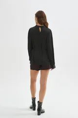 Blusa de poliéster color negro con cuello alto, mangas largas, diseño holgado, detalles de frunces y lazo ajustable en la cintura.