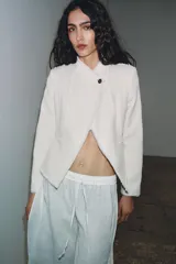 Blazer de cuello alto confeccionada en mezcla de algodón con textura tipo tweed. Presenta un diseño con acabados desflecados, cierre frontal con un solo botón y bajo con detalle peplum.
