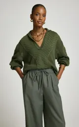 Sweater de punto color verde militar, con cuello polo y escote en V, mangas largas abullonadas con puños ajustados y tejido con tramas geométricas combinadas.