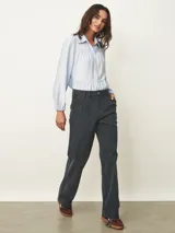 Pantalón de corte recto y tiro medio, confeccionado en tela de pana color azul piedra. Presenta cierre frontal con botón, bolsillos laterales y detalle de pinzas en la cintura.