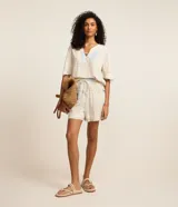 Blusa de manga corta en viscosa color beige, con escote en V con detalle de tira y cuenta de madera, y estampado geométrica y de follaje en tonos celestes.