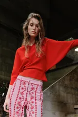 Jersey rojo de punto con escote en V pronunciado tanto en el delantero como en la espalda, mangas largas y diseño entallado en la cintura con caída acampanada.
