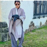 Ruana de material símil cachemira, de diseño bicolor en tonos gris y lila con bandas anchas en los bordes.