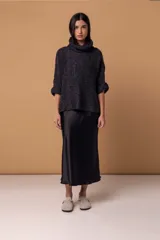 Sweater tipo poncho de tejido de punto grueso en color negro, con cuello alto tipo polera y mangas tres cuartos con puños vueltos.