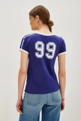 Remera estilo ringer, color azul oscuro con cuello y ribetes en las mangas en color blanco. Presenta el número "99" estampado en blanco en el frente.