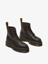 Bota Dr. Martens modelo Sinclair, color marrón oscuro, con plataforma gruesa y suela ranurada. Confeccionada en cuero Crazy Horse, presenta un aspecto desgastado. Incluye cierre frontal de cremallera extraíble, cordones y costura amarilla en el ribete.