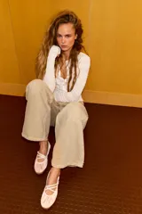 Bailarina deportiva de estilo casual confeccionada en material con efecto satinado color rosado. Presenta tiras elásticas cruzadas en el empeine con cierre de hebilla ajustable, punta redonda y suela de goma flexible.