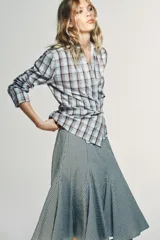 Camisa de algodón con estampado a cuadros en tonos celeste y marrón. Presenta cuello solapa, escote pico y diseño cruzado con lazada frontal.