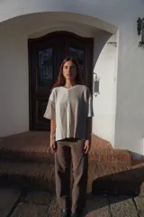 Remera de tejido de punto, manga corta, con diseño bicolor en negro y beige. La prenda es de corte holgado y presenta un ligero acanalado vertical.