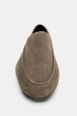 Mocasín plano de serraje color marrón, con diseño de copete subido, pespuntes decorativos en el cuerpo y punta ligeramente perfilada.