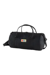 Bolso de viaje Fjallraven modelo Vardag Duffel 30, color negro, con logo rectangular de la marca en el frente. Tiene doble asa de mano y correa de hombro ajustable.
