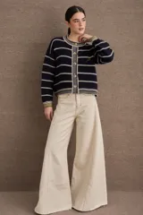 Cardigan de punto con diseño a rayas horizontales en azul marino y beige. Presenta cuello redondo, cierre frontal con botones grandes y mangas largas con puños acanalados en tono verde oliva. Incluye un pequeño bordado de una raqueta de tenis en el lateral.