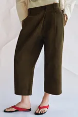 Pantalón cropped de tiro medio con diseño de pinzas en el delantero, trabillas para cinturón, bolsillos laterales y bolsillos de vivo en la parte trasera. Cierre frontal con cremallera y botón.
