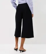Pantalón pantacourt negro de sarga con largo midi y caída estructurada, cuenta con cintura de terminación limpia y pinzas frontales.