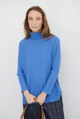 Polera de punto acanalado en color azul, con cuello alto y mangas largas. Presenta un diseño de corte recto y tejido ligero.