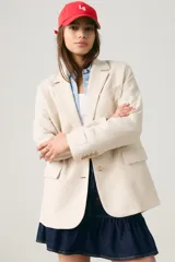 Blazer holgado color beige, de corte clásico con solapas de muesca, cierre frontal de un botón, bolsillos con solapa y mangas largas con botones en los puños.