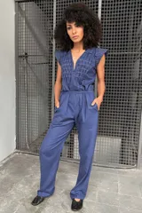 Mono azul de lino y algodón texturizado con plisados de pespuntes de color en contraste. Tiene lazo en la cintura, fuelle en la espalda y mangas texturizadas.