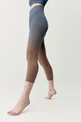 Calza deportiva corta de diseño seamless, con efecto degradado que transiciona del gris azulado en la parte superior al marrón en las piernas.