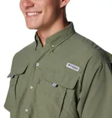 Camisa de manga corta Columbia, diseñada para actividades al aire libre y pesca. Presenta cuello abotonado, cierre frontal con botones, cuatro bolsillos frontales con solapa y ventilación en la espalda. Confeccionada en tejido técnico de secado rápido con protección solar.