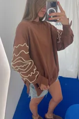 Buzo azul marino de tejido sin friza, con cuello redondo y bordados blancos con diseño de flores estilizadas en las mangas.