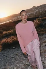 Sweater de punto color rosado con cuello redondo y manga larga, de bajo asimétrico con acabados en rib.