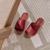 Sandalias chatas de cuero color rojo, con faja ancha en el empeine y suela plana.