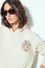 Buzo canguro color marrón con capucha y estampado de un corazón anatómico en azul en el pecho. De silueta relajada y calce cómodo.