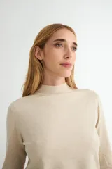 Polera de punto color beige, con cuello alto y mangas largas, de diseño básico y ajuste clásico.