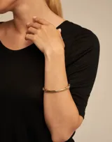 Pulsera dorada con cuentas redondas y un abalorio rígido.