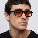 Lentes de sol con montura rectangular de color negro y cristales en tono naranja. Presentan un diseño contemporáneo con esquinas redondeadas y protección UV400.