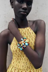 Pack de pulseras elásticas compuestas por una mezcla de cuentas de resina y acrílico, incluyendo formas de flores, hojas y cuentas ovaladas y redondas en una amplia gama de colores vibrantes.