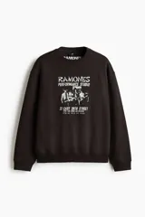 Buzo negro de cuello redondo con estampa frontal inspirada en la banda Ramones, hombros caídos y corte holgado.