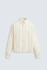 Camisa relaxed fit de manga larga con cuello solapa, confeccionada en tejido con mezcla de algodón. Presenta un estampado de rayas verticales en tonos beige, blanco y marrón. Incluye un bolsillo plastrón en el pecho, puños con botón y aberturas laterales en el bajo. Cierre frontal de botonadura.