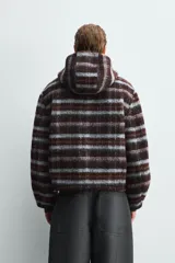 Cazadora de corte boxy fit confeccionada en tejido con lana, con diseño de cuadros en tonos marrones y celestes. Presenta cuello con capucha, cierre frontal con cremallera, manga larga y bolsillos ocultos en las costuras laterales.