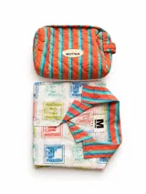 Pijama de algodón de la marca Mutma, compuesto por una camisa de manga corta con solapas a rayas y short a juego, con estampado de estampillas de colores. Incluye un necesaire acolchado con el mismo estampado a rayas en tonos naranja y celeste.