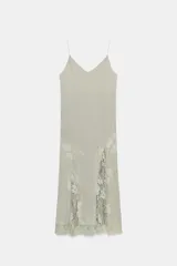 Vestido largo lencero de tejido fluido en color gris verdoso, con escote en V, tirantes finos y detalles de encaje a tono en el bajo y los laterales, además de una abertura frontal.