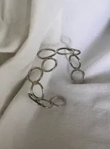 Pulsera rígida plateada hecha en alpaca, con diseño de eslabones circulares.