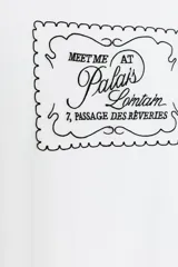 Camiseta blanca de manga corta y cuello redondo, con aplicación de organza y texto negro a contraste en el pecho.