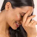 Anillo dorado con piedra central rectangular color borgoña y dos diamantes circulares a cada lado.